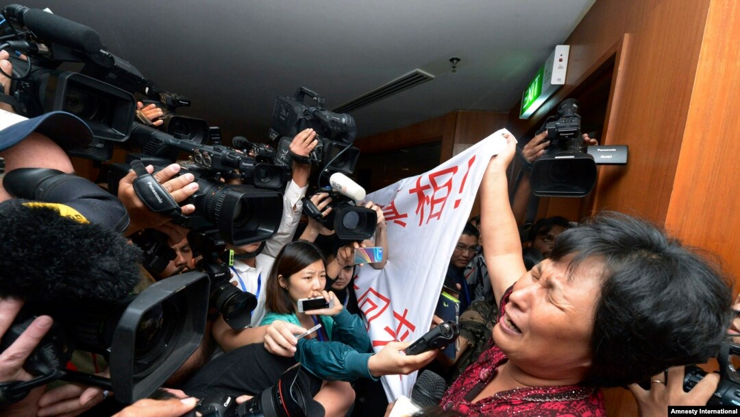 A Chinese relative of passengers aboard a missing Malaysia Airlines plane cries as she holds a banner in front of journalists reading 'We are against the Malaysian government for hiding the truth and delaying the rescue. Release our families unconditional