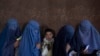 FILE - Afghan women wait to receive cash at a money distribution point organized by the World Food Program, in Kabul, Afghanistan, on Nov. 20, 2021. 