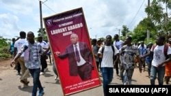 Des partisans tiennent une affiche à l'effigie de l'ancien président Laurent Gbagbo dans sa ville natale de Mama, à Gagnoa, en Côte d'Ivoire, le 13 juin 2021.