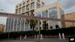 Greek forensic experts search outside the private Greek television station Skai, after a powerful bomb explosion, in Faliro, Athens, Dec, 17, 2018. 