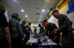 FILE - Marines of the 24th Marine Expeditionary Unit process Department of State personnel for evacuation at Hamid Karzai International Airport, in Kabul, Afghanistan, Aug. 15, 2021.