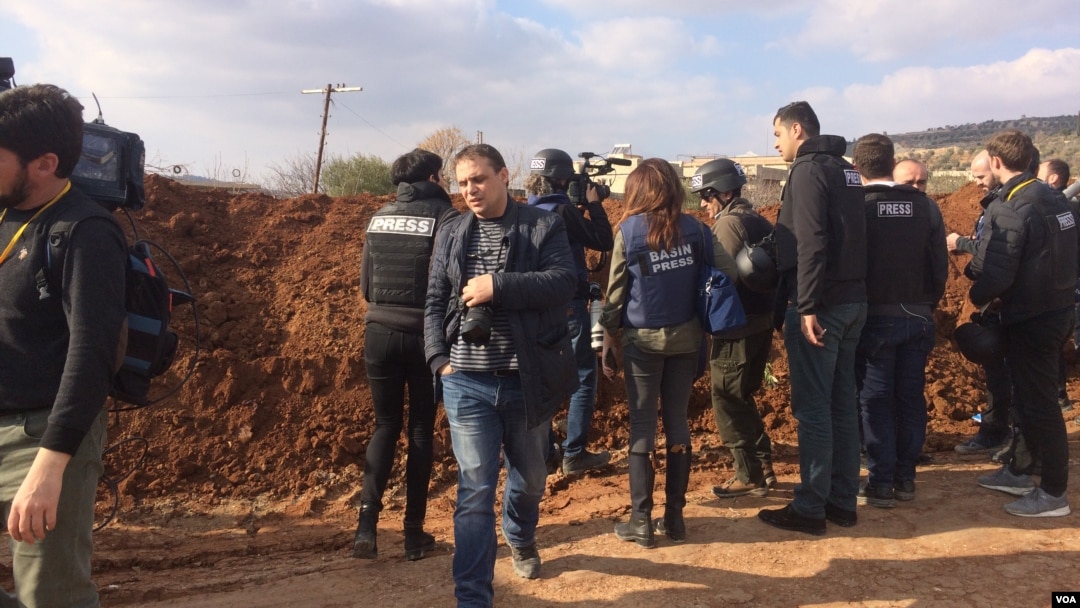 Reporters hurry up what looks to be a berm with views of mountainsides controlled by apposing militaries on Feb. 1, 2018 in Marin, Syria. (H.Murdock/VOA)