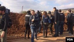 Reporters hurry up what looks to be a berm with views of mountainsides controlled by apposing militaries on Feb. 1, 2018 in Marin, Syria. (H.Murdock/VOA)