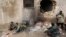 Rebel fighters rest near a hole in the wall by a fire on the outskirts of the northern Syrian town of al-Bab, Jan. 15, 2017. 