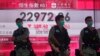 Riot police wearing face masks stand guard in front of a bank electronic board showing the Hong Kong share index at Hong Kong Stock Exchange, May 28, 2020.