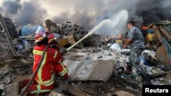 Firefighters spray water on a fire following an explosion in Beirut's port area, Lebanon, Aug. 4, 2020. 