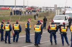 Police officers block the road at the Austrian border in Hegyeshalom, northwestern Hungary, Tuesday, March 17, 2020. By noon an almost 20-kilometer long line of cars waited on the Austrian side of the border.