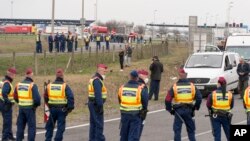 Police officers block the road at the Austrian border in Hegyeshalom, northwestern Hungary, Tuesday, March 17, 2020.