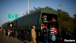 Migrantes venezolanos se suben a camiones militares para viajar gratis desde el servicio fronterizo ecuatoriano-peruano hasta Tumbes, después de procesar sus documentos, en las afueras de Tumbes, Perú, el 15 de junio de 2019.