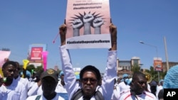 FILE — A doctor displays a poster as he and other medical staff take part in a protest, in downtown Nairobi, on March 22, 2024.