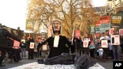 Para pengunjuk rasa membawa plakat di depan Parlemen di London, Jumat, 29 November 2024 saat anggota parlemen Inggris memberikan persetujuan awal terhadapRUU Eutanasia. (Alberto Pezzali/AP)