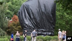 FILE - Residents and visitors look over the covered statue of Confederate General Robert E. Lee in Emancipation park in Charlottesville, Va., Aug. 23, 2017. 