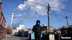 Seorang pria berjalan di dekat pembangkit listrik tenaga batu bara di Harbin, Provinsi Heilongjiang, China, 27 November 2019. (Foto: REUTERS/Jason Lee)