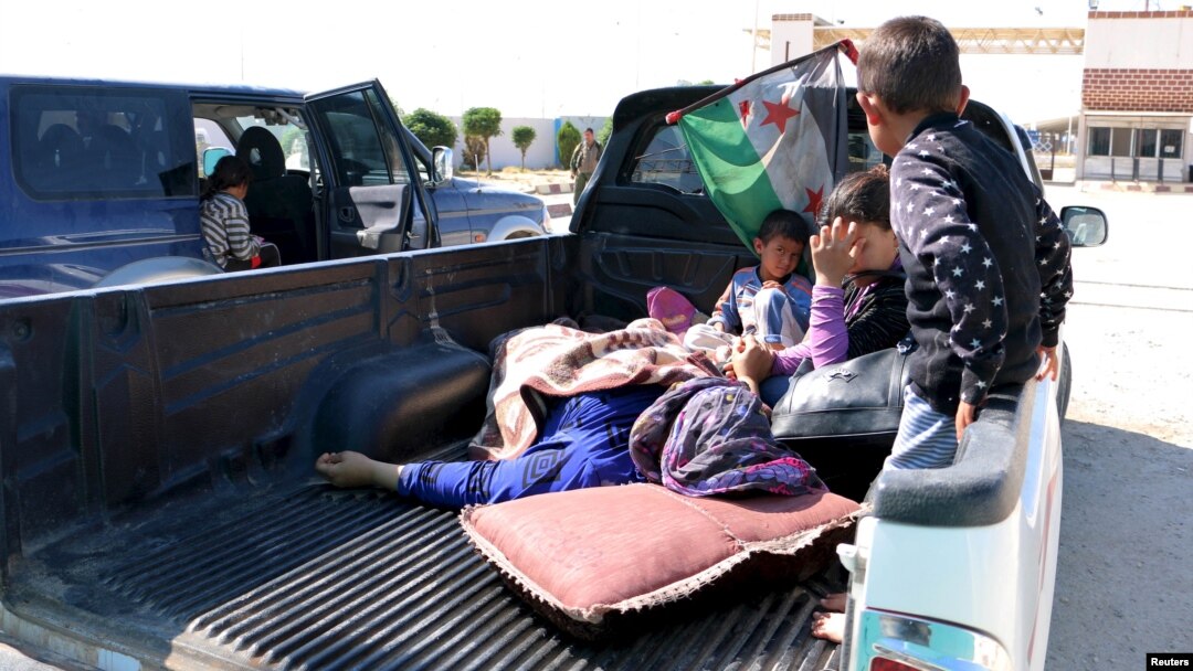 FILE - Civilians, who were wounded by what activists said was violence caused by Islamic State fighters in Kobani, wait with their relatives to cross into Turkey at the Syrian-Turkish border crossing of Tel Abyad, Syria June 25, 2015. 