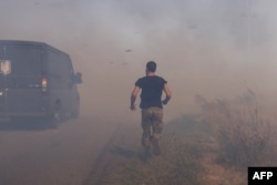 A Ukrainian serviceman runs to help farmers extinguish a burning field near Pokrovsk, Donetsk region, on September 16, 2024, amid the Russian invasion of Ukraine.