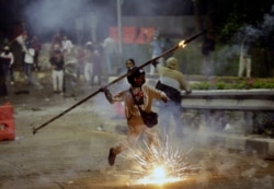 A student protester throws a burning stick at riot police officers during a clash in Jakarta, Indonesia, Sept. 30, 2019.