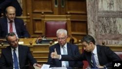 Greece's Prime Minister Kyriakos Mitsotakis gives a thumbs up to Finance Minister Christos Staikouras as Deputy Prime Minister Panagiotis Pikrammenos looks on during a parliamentary session in Athens, July 20, 2019.