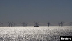 FILE - A ship passes offshore windmills on the coast near Copenhagen, Denmark, April 4, 2015.