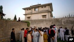 FILE - local residents gather outside a house in Abbottabad, Pakistan, where al-Qaida leader Osama bin Laden was killed in a raid the day before.