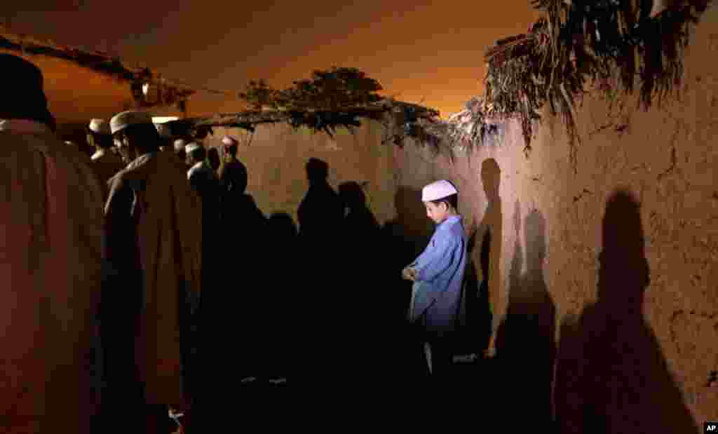 Pakistani men and children, who fled their villages due to fighting between security forces and militants in Pakistan's tribal area of Bajur, attend prayers in a mosque on the outskirts of Islamabad, Pakistan, July 27, 2012.