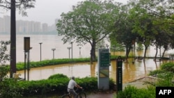 ผู้ปั่นจักรยานฝ่าน้ำท่วมใกล้แม่น้ำ ในเมืองชิงหยวน มณฑลกวางตุ้น เมื่อ 21 เม.ย. 2024 ในภาวะอุทกภัยที่ทางการจีนระบุว่าเป็นเหตุรุนแรง "ครั้งหนึ่งในศตวรรษ" (Photo by AFP)