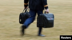 一名白宫军事随从拿着带有核打击密码的手提包在白宫南草坪陪同拜登总统走向“海军陆战队一号”专用直升机。 (2021年2月16日)