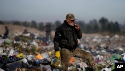 Un anciano hace una pausa para fumar un cigarrillo mientras revisa la basura en un vertedero en busca de materiales para vender en Luján, Argentina, el jueves 29 de agosto de 2024. AP