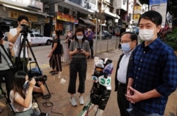 Pro-democracy legislator Ted Hui, right, talks to reporters outside a police station in Hong Kong Wednesday, Nov. 18, 2020.