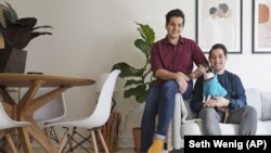 In this Monday, Nov. 25, 2019 photo, Zachariah Mohammed, left, Pete Mancilla, and their dog Remy pose for a picture in their New York apartment. (AP Photo/Seth Wenig)