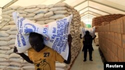 Una persona carga bolsas de alimentos secos de un almacen del Programa Mundial de Alimentos para distribución a refugiados de Sudán del Sur en el campamento de refugiados de Lamwo, Uganda, el 16 de junio de 2017.