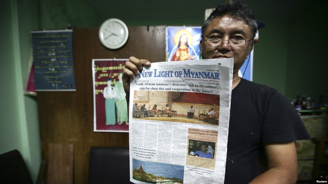Pemimpin redaksi Than Myint Tun memegang contoh edisi baru koran The New Light of Myanmar. (Reuters/Minzayar)