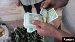 FILE - A vendor counts Syrian currency notes in Damascus, November 13, 2012. 