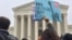 A protester waves a sign at a rally outside the U.S. Supreme Court in Washington, April 25, 2018 (V. Macchi/VOA). Opponents of the Trump administration’s travel ban say the policy discriminates against Muslims, 