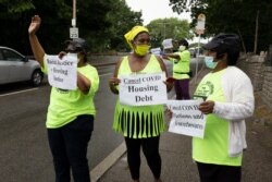 FILE - Annie Gordon, left, Gabrielle Rene, center, and Jenny Clark, right, rally for protection from evictions amid the coronavirus pandemic, June 27, 2020, in the Mattapan neighborhood of Boston.