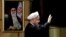 Iranian President Hassan Rouhani waves as he stands next to a portrait of Iran's Supreme Leader Ayatollah Ali Khamenei, after he registered for February's election of the Assembly of Experts, the clerical body that chooses the supreme leader, at Interior 