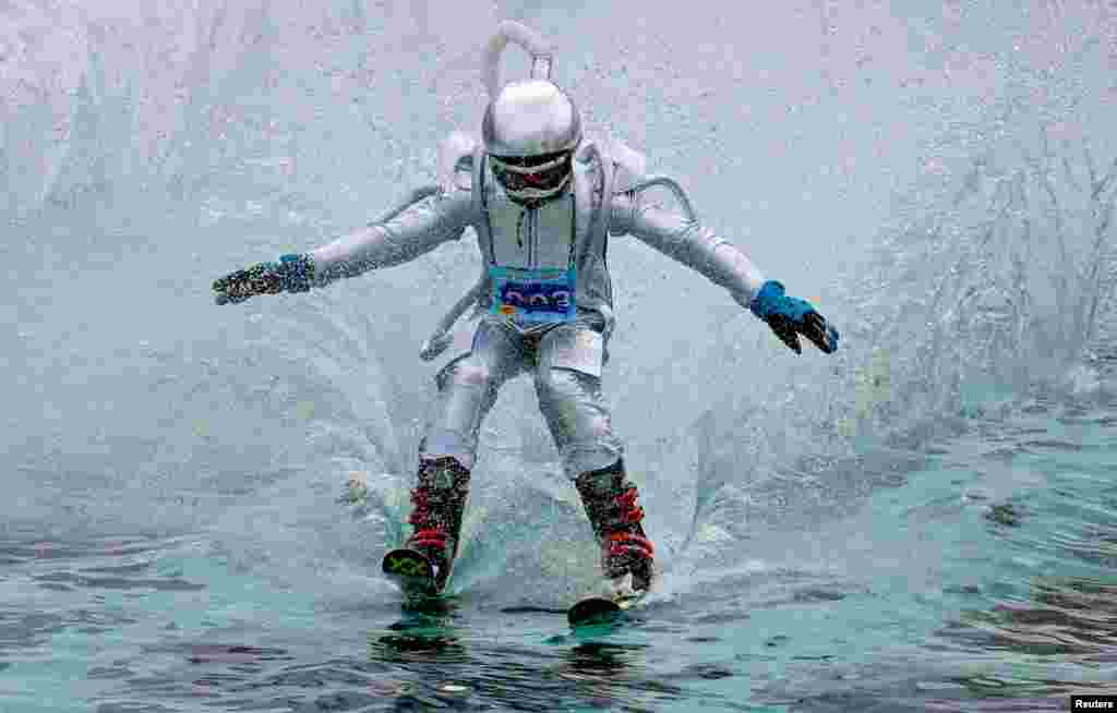 A skier in a festive costume attempts to cross a pool of water at the foot of a ski slope while competing in the annual Gornoluzhnik amateur event to mark the end of the ski season at the Bobrovy Log ski resort in the suburbs of the Siberian city of Krasnoyarsk, Russia, April 14, 2019.