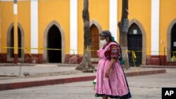 Una mujer indígena con una máscara protectora camina cerca del cementerio en medio de la nueva pandemia de coronavirus en Quetzaltenango, Guatemala, el sábado 8 de agosto de 2020.