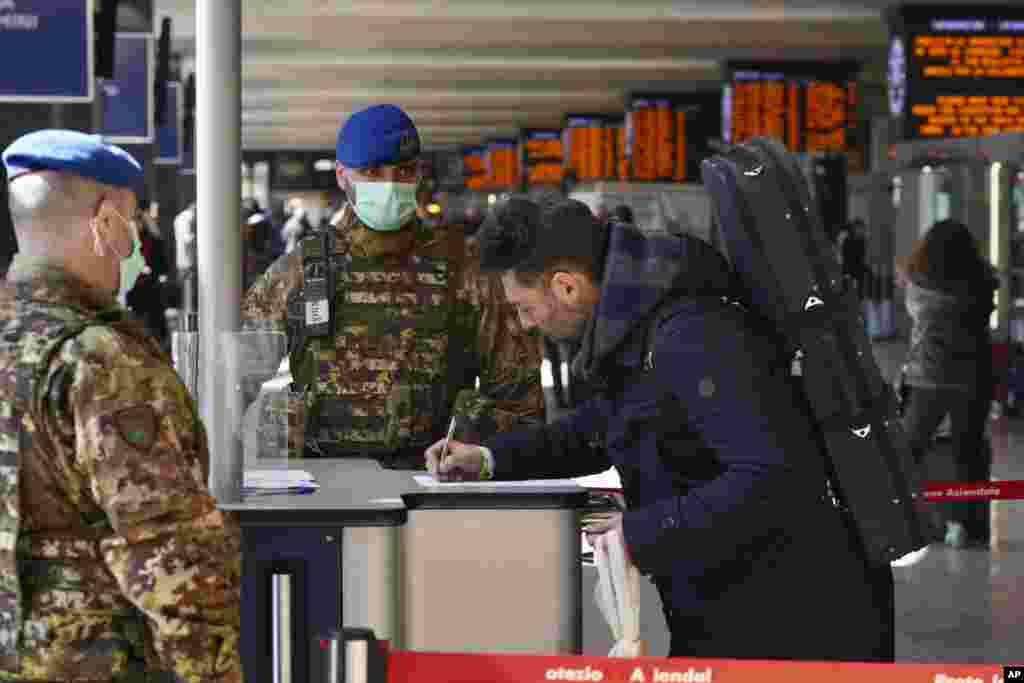 A traveler fills out a form at a check point set up by border police inside Rome&#39;s Termini train station, Italy. The government expanded a coronavirus containment order previously to include the whole country, with soldiers and police enforcing bans.