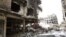 FILE - Rubble and heavy damage remain on a deserted street during a government escorted visit to Yarmouk refugee camp in Damascus, Syria, April 9, 2015. The United Nations brokered a deal to relocate some IS fighters and their families.