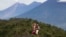 In this June 8, 2018 photo, a couple of tourists kiss with the view of the volcanoes, Fuego, left, Acatenango, center, and Agua, right, in the background, from a point in the climb to the Pacaya Volcano, in San Francisco de Sales, Guatemala.