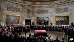 ທຸງ​ຊາດ​ທີ່​ປົກ​ຄຸມ​ສົບ​ຂອງ​ອະ​ດີດ​ປະ​ທາ​ນາ​ທິ​ບໍ​ດີ​ສະ​ຫະ​ລັດ ທ່ານ George H.W. Bush ທີ່​ຈັດ​ໄວ້​ໃນຫ້ອງໂຖງ​ Rotunda ໃນຕຶກ​ລັດ​ຖະ​ສະ​ພາ, 3 ທັນ​ວາ 2018.