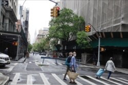 FILE - Pedestrians wearing protective masks cross Irving Place in New York during the coronavirus pandemic, May 23, 2020.