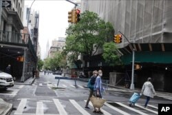 FILE - Pedestrians wearing protective masks cross Irving Place in New York during the coronavirus pandemic, May 23, 2020.