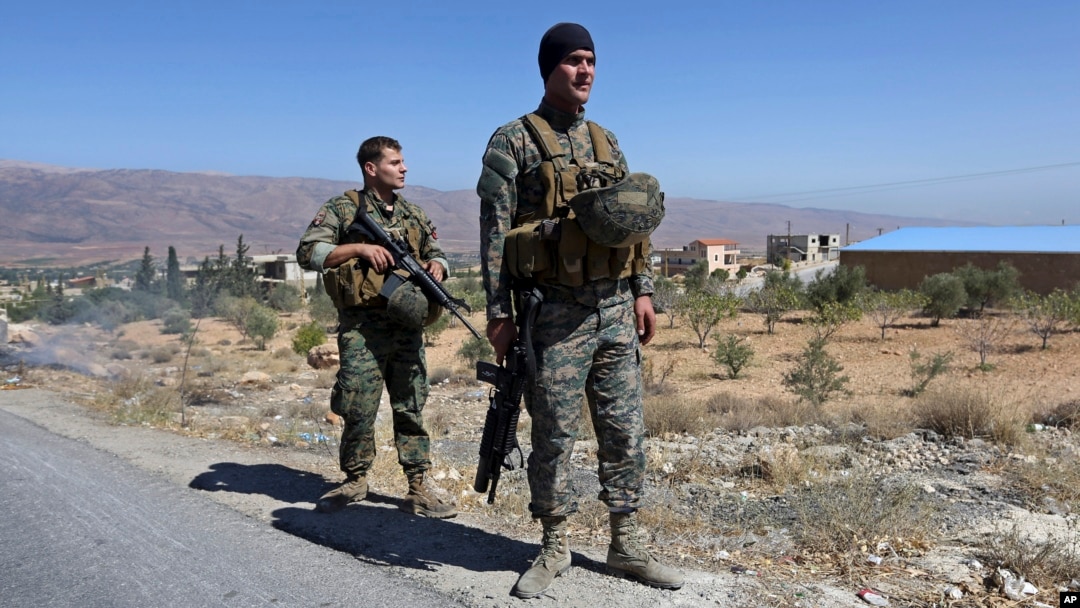 FILE - Lebanese army soldiers stand guard at an entrance to Arsal, a predominantly Sunni Muslim town near the Syrian border in eastern Lebanon, Aug. 4, 2014.