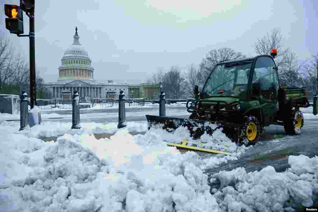 Seorang petugas membersihkan jalan dari salju dekat gedung Capitol. Badai salju terakhir menghantam negara-negara bagian mid-Atlantik AS beberapa hari sebelum musim semi dimulai, Washington, DC, 17 Maret 2014.