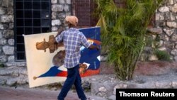 A man carries a painting of slain President Jovenel Moise in the Petion-Ville neighborhood in Port-au-Prince, Haiti, July 16, 2021.