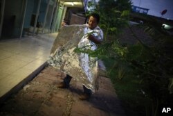 A Honduran migrant, who was returned from the U.S. the previous day, folds the emergency blanket U.S. immigration officials gave him as he camps with other migrants outside a Mexican immigration office in Matamoros, Mexico, Aug. 4, 2019.