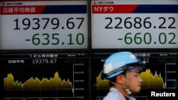 Seorang pria berjalan melewati papan elektronik yang menunjukkan angka indeks rata-rata Nikkei (kiri) dan Dow Jones Industrial Average di Tokyo, Jepang, 4 Januari 2019. 