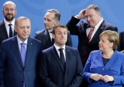 German Chancellor Angela Merkel, front right, speaks with French President Emmanuel Macron, front center, during a group photo at a conference on Libya at the chancellery in Berlin, Germany, Jan.19, 2020.
