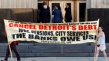 Protesters carry a banner calling for Detroit's debt to be cancelled as people enter the federal courthouse for day one of Detroit's municipal bankruptcy hearings in Detroit, Michigan July 24, 2013. 